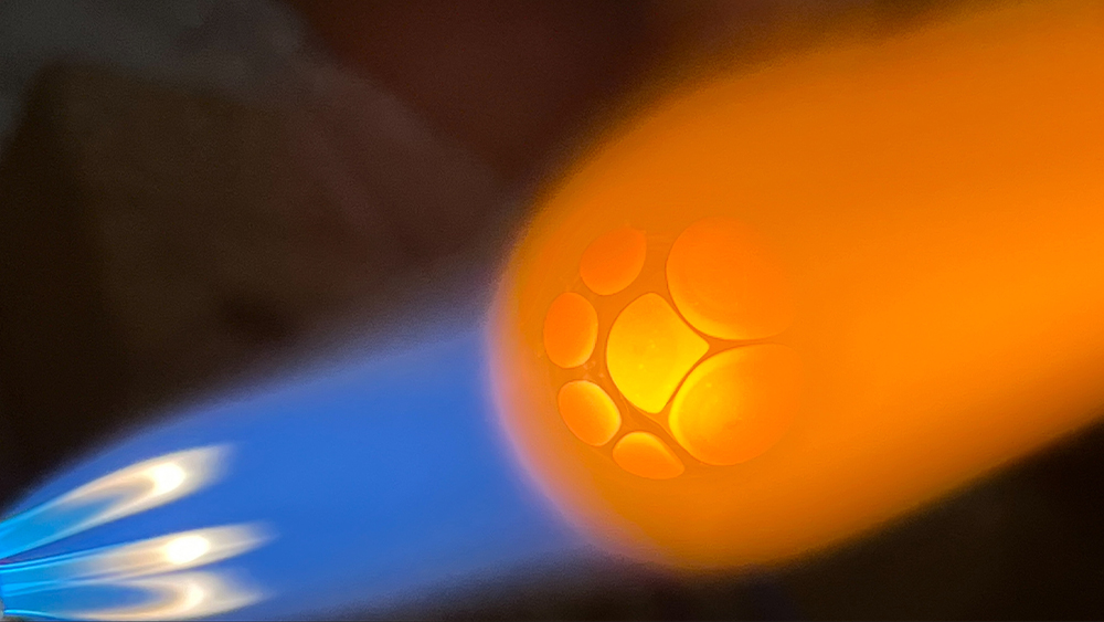 The molten glow of a glass piece takes form under intense flame, where art and engineering meet.