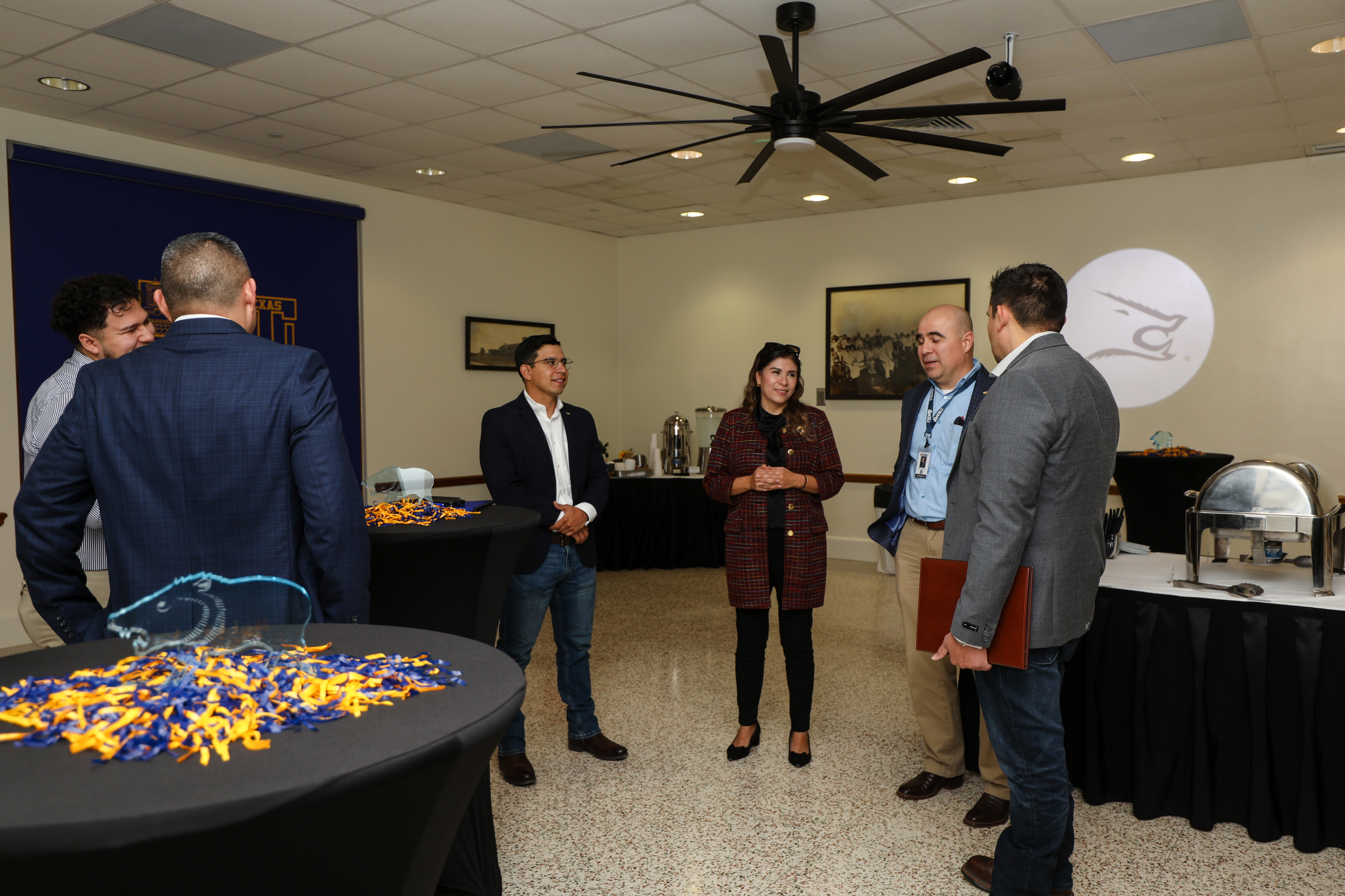 Several people stand speaking in the interior space of Founders Room.